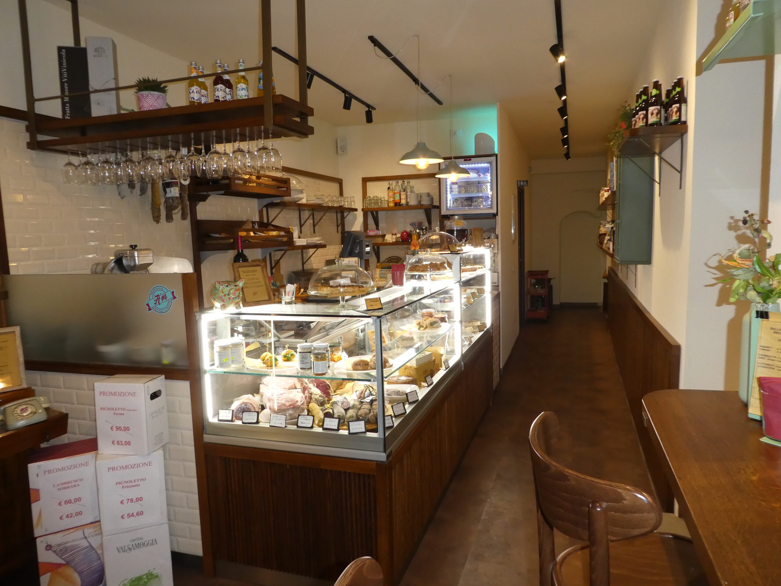 Progetto su misura: ottimizzazione di piccoli spazi con arredi professionali e soluzioni espositive che integrano bottega, gastronomia e cucina.