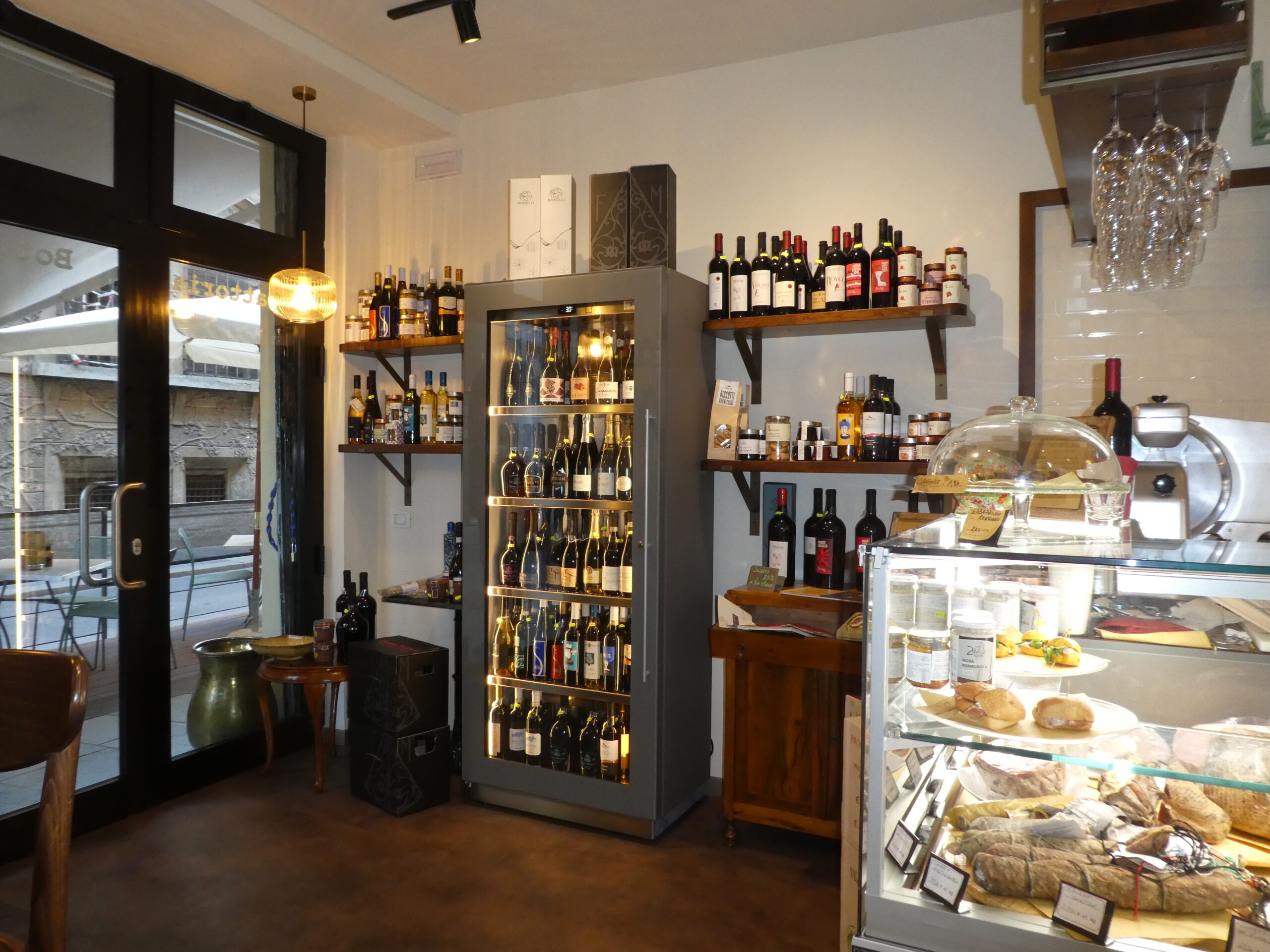 Progetto su misura: ottimizzazione di piccoli spazi con arredi professionali e soluzioni espositive che integrano bottega, gastronomia e cucina.